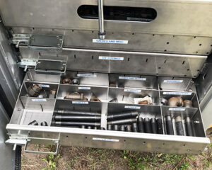 Image shows a drawer of a Fisk tank carrier truck pulled out and each compartment labeled and filled with propane tank setting tools.